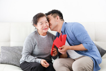 Chinese New year concept : Asian Senior mother give Red envelope to her son for gift money