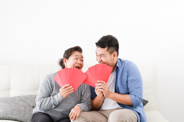 Fototapeta na wymiar Chinese New year concept : Asian Senior mother give Red envelope to her son for gift money