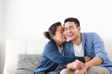 Asian senior mother in blue shirt  kiss her son happy and smile face in living room