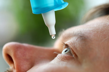 Man putting liquid drops in his eye solving vision problem