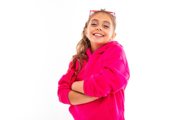 Fashionable teenager girl in pink hoody and with pink sunglasses gesticulates, portrait isolated on white background