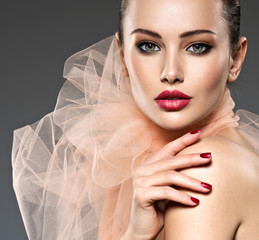 fashion woman with stylish makeup, red nails and lips wearing beige scarf