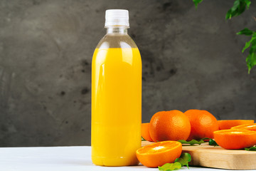 Bottle of fresh orange juice on wooden table against white brick wall background