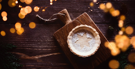 Traditional homemade Christmas pie on dark wooden background, with romantic lights and copy space / banner, header / flat lay, top view