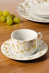 Coffee cup set with saucer on a wooden table with set of dishes in the background