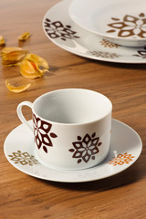 Coffee cup set with saucer on a wooden table with set of dishes in the background