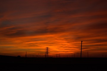 Deep and intense colors of a sunset in a suburb with silhouette of electric poles