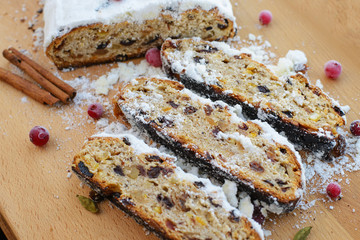 Stollen traditional german christmas baking. With raisins, candied fruit, cranberries, sprinkled with powdered sugar. Tasty homemade sweets. Top view, selective focus. Free baking recipes ideas.