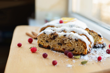 Stollen traditional german christmas baking. With raisins and candied fruit, cranberries, sprinkled with powdered sugar. Tasty homemade sweets. Close-up selective focus. Free baking recipes ideas.