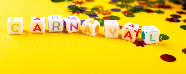 Festive yellow background with colorful carnival mask cubes with dutch text Carnaval. Greeting card concept voor carnival and party. Copy space, selective focus. Banner