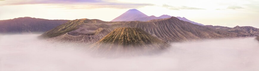 View from above, stunning panoramic view of the Mount Semeru, Mount bromo and the Mount Batok surrounded by clouds during a beautiful sunrise. East Java, Indonesia.