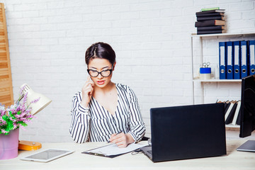 business girl sits at a computer in the Office paper folders
