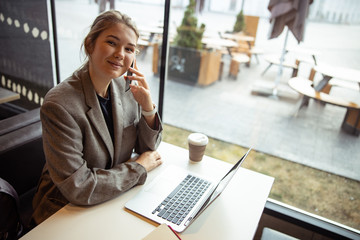 Joyful young woman talking on cellphone in cafe