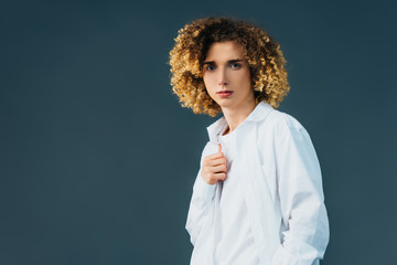 curly teenager in total white outfit isolated on green