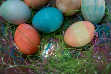 colorful dyed easter eggs gathered on a table with easter grass