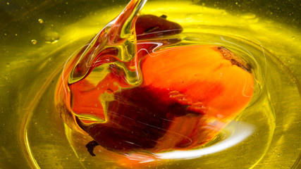 Red Palm seed dropped in cooking palm oil with a splash in glass. Organic palm oil can be processed for food industry and produce energy as biodiesel and important agriculture economy in tropical Asia