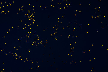 Dark black background with golden confetti in the shape of stars.