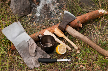 Old axe on green grass top view. building background. justice on the grass concept.Equipment for trekking.Knife, metal mug and wooden spoon.