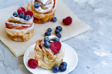 Delicious and beautiful berry rose puff pastries. Classic winter sweet dessert on blue background. French new year dessert.