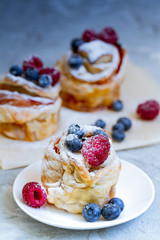 Delicious and beautiful berry rose puff pastries. Classic winter sweet dessert on blue background. French new year dessert.