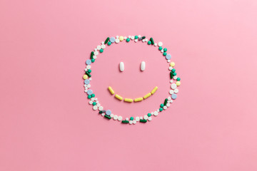 Composition of pills and capsules on a pink background in the form of a smile. Happy emotions....