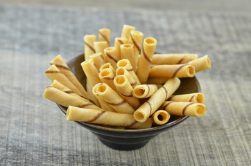 Vanillia waffle roll stick in black ceramic bowl