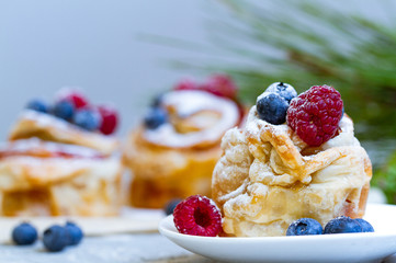 Delicious and beautiful berry rose puff pastries. Classic winter sweet dessert on blue background. French new year dessert.