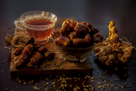 Dates tea in transparent glass cup along with some fennel seeds, cinnamon sticks and ginger well mixed and put together in tea.The horizontal well lit upshot of dates tea in a transparent glass cup.