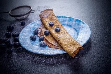Crepes with blueberries. Homemade pancakes, crepes on blue plate,