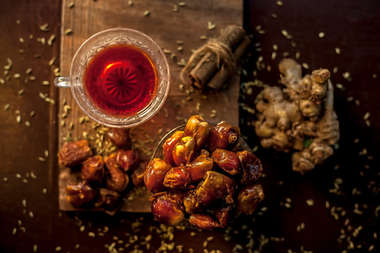 Dates tea in transparent glass cup along with some fennel seeds, cinnamon sticks and ginger well mixed and put together in tea.The horizontal well lit upshot of dates tea in a transparent glass cup.