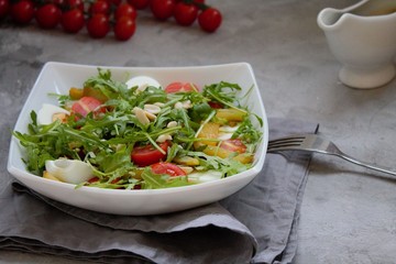Healthy vegetable salad with cherry tomatoes, arugula, egg, caramelized pear and nuts. Vegetable salad with sauce. Salad with dressing. Salad with an egg. Salad with pear. Vegetarian