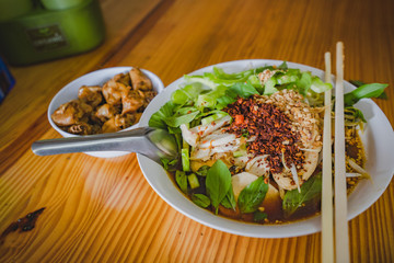 Chicken noodles soup in bowl at noodle shop street .	