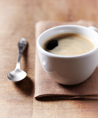 Cup of coffee on brown wooden background. Close up.