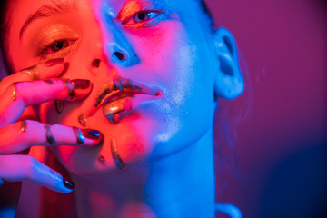  Fashion model metallic silver lips and face woman in neon uv blue and   purple lights, posing in studio, beautiful girl, glowing make-up,   colorful make up. 