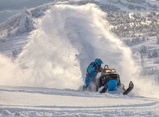Pro snowmobiler makes a turn and lets a flurry of snow spray from under the caterpillar. sports...
