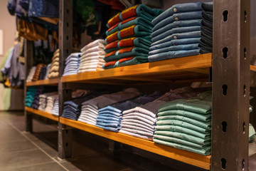 Obraz na płótnie Canvas clothes are neatly stacked on the shelves in the store. Shirts, jeans