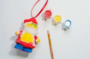 Christmas children's crafts on a white background, gypsum Santa Claus painted with paints, children's art