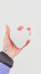 Heart-shaped snowball in a male hand in winter