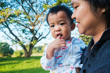 Infant baby boy hold by mom in park morning light