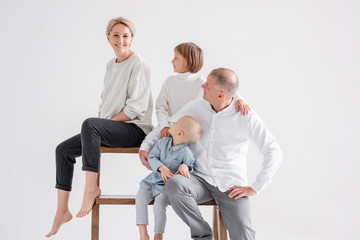 Obraz premium Happy joyful family pregnant mom positive dad and two charming kids brother and sister posing together in the studio. Happy full family concept. Copyspace