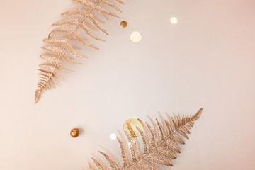 Festive composition. Shiny Christmas decorative floral fern branches, confetti, gold glitters on beige background. Flat lay. Copy space. Stylish christmas concept Minimalism