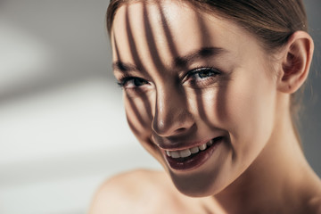 portrait of smiling girl with shadows on face on grey