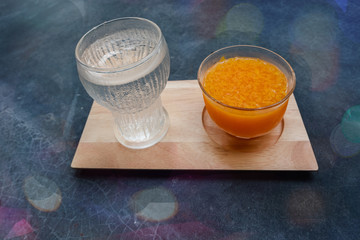 Glass of fresh orange juice and glass of water on a wooden tray On the marble table..Image contain certain grain or noise and soft focus bokeh.