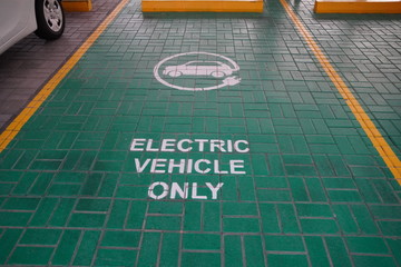 Green electric vehicle charging station sign in a parking bay. Electric vehicle parking space. Electric car charging station.
