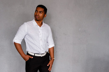 Obraz premium Successful handsome confident African American businessman posing against the background of a gray wall in formal clothes. Concept of entrepreneurial successful young business people. Copyspace