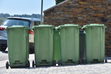 Green trash cans are standing against the wall. Garbage containers for sorting garbage in a European city