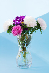 bouquet of flowers in a crystal vase.Autumn garden asters, pink, purple and white. Blue background. sunlight - 309198625