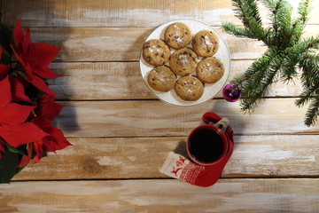 top view on christmas and new year still life with cookies, cup of coffee, gift sock, new year tree with ball, poinsettia flower on wooden background