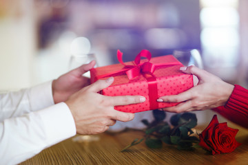 Man giving a christmas present to his girlfriend. Cheerful couple with gift in hands enjoying together on Christmas eve. Winter holidays concept. Lovers give each other gifts. Valentine's Day concept.