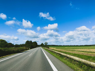 Empty asphalt road, blue sky with clouds